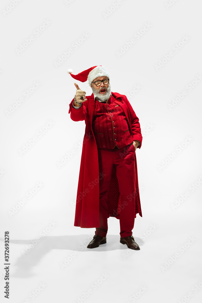 Thumb up. Modern stylish Santa Claus in red fashionable suit isolated on white background. Looks like a rockstar. New Year and Christmas eve, celebration, holidays, winter's mood, fashion.