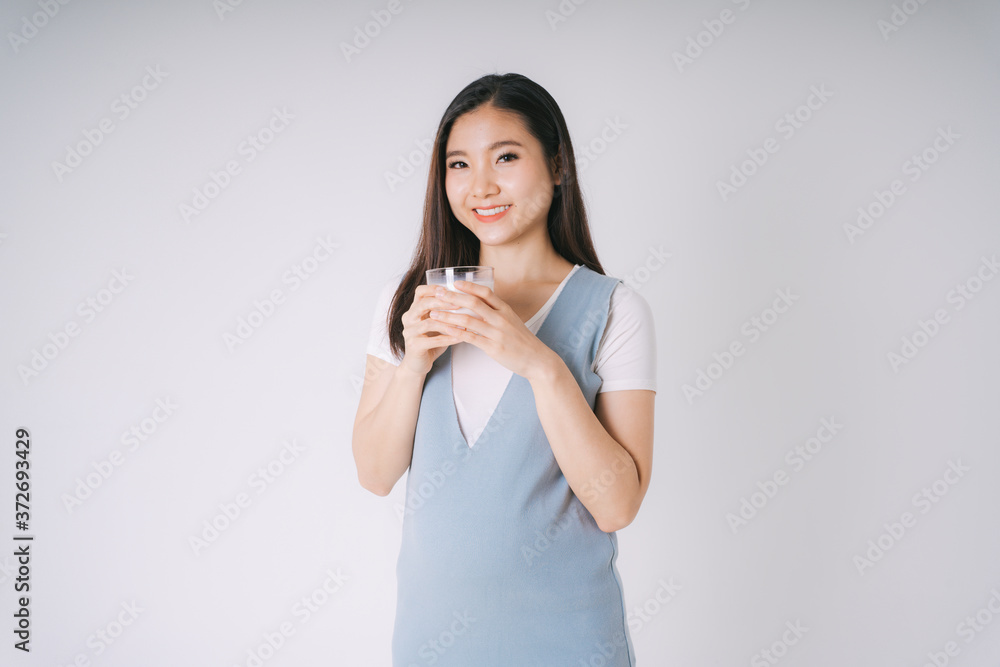 Beautiful pregnant asian woman with a cup of fresh isolate over white background. Beautiful pregnant asian woman with a cup of fresh isolate over white background.