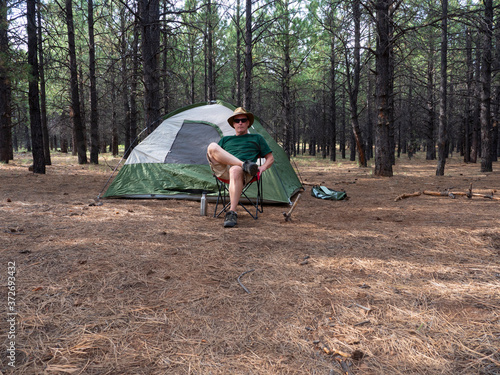 A man resting after setting up camp in the forest