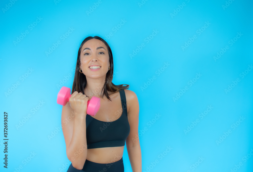 Beautiful woman in sport clothes with a dumbbell smiling Beautiful woman in sport clothes with a dumbbell smiling