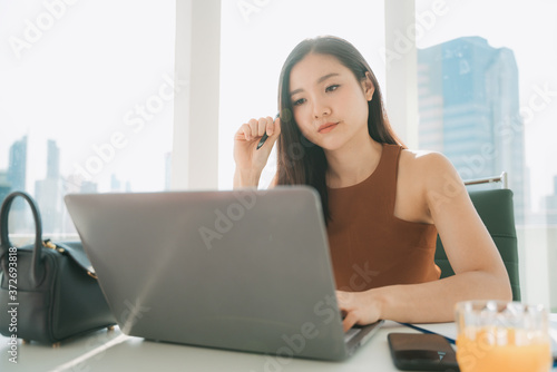 Thoughtful asian thai businesswoman working on laptop in office working place. Free Download Thoughtful asian thai businesswoman working on laptop in office working place. - GFXLoad