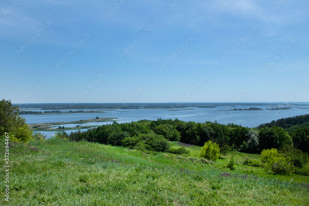 View of the wide beautiful Dnieper River from the side of a large green meadow