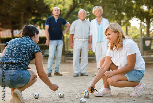 Pleasant smiling family playing petanque in outdoor photo