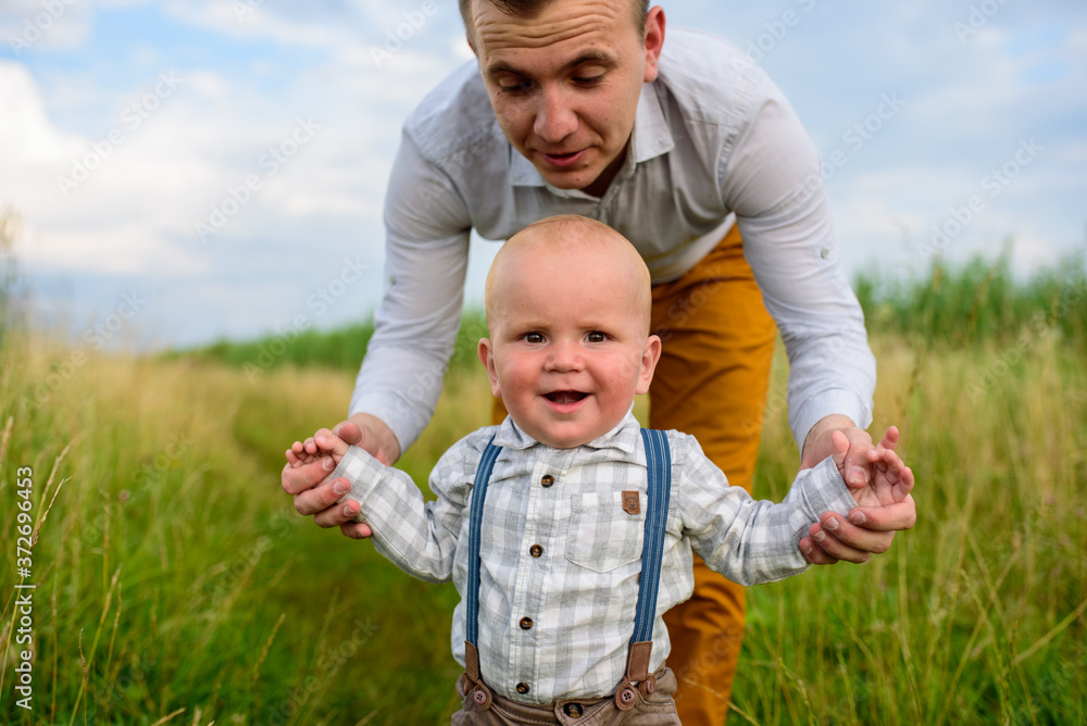 A father teaches his one-year-old son to walk. A father teaches his one-year-old son to walk.