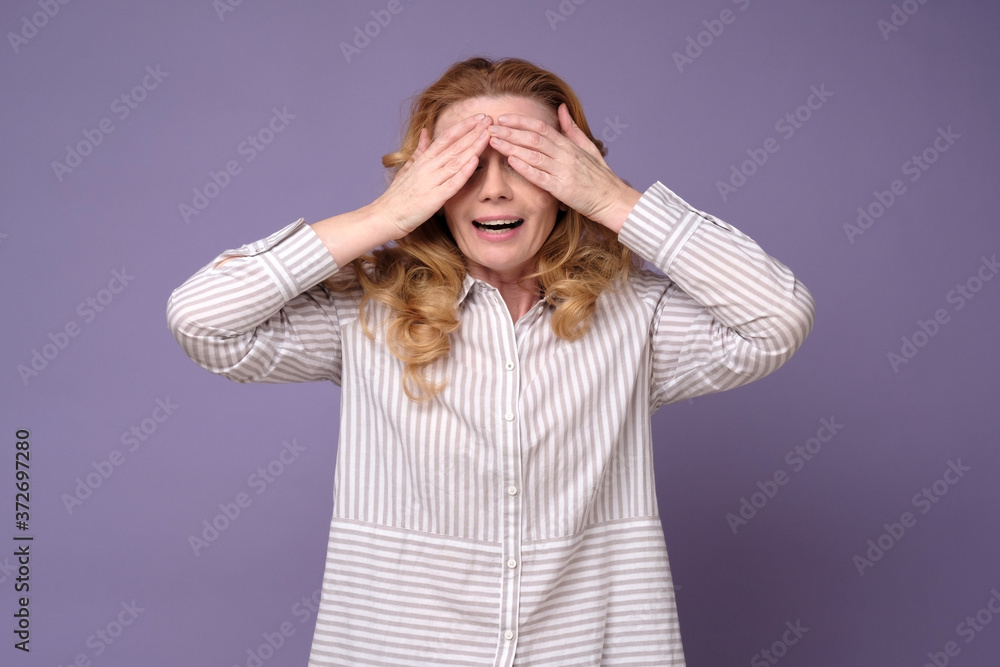 Caucasian mature woman covering eyes waiting for surprise. Studio shot Caucasian mature woman covering eyes waiting for surprise. Studio shot
