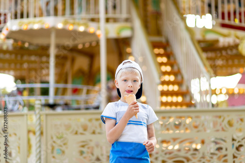 happy child boy 5-6 years old walking in an amusement Park and eating ice cream. Children lifestyle