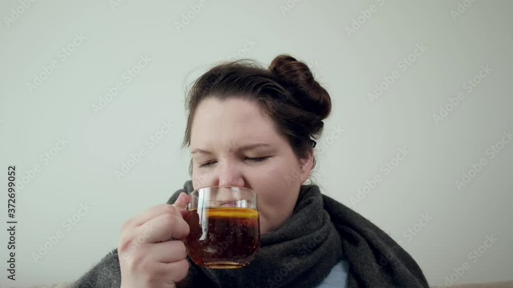 A girl is ill and is drinking hot tea from a mug. A pet dog is walking nearby. A girl is ill and is drinking hot tea from a mug. A pet dog is walking nearby.
