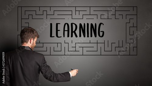 businessman drawing maze with LEARNING inscription, business education concept