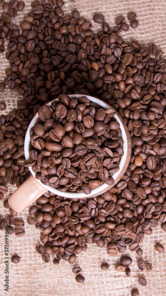 Mug full of coffee beans on the background of the bag,large Plenum