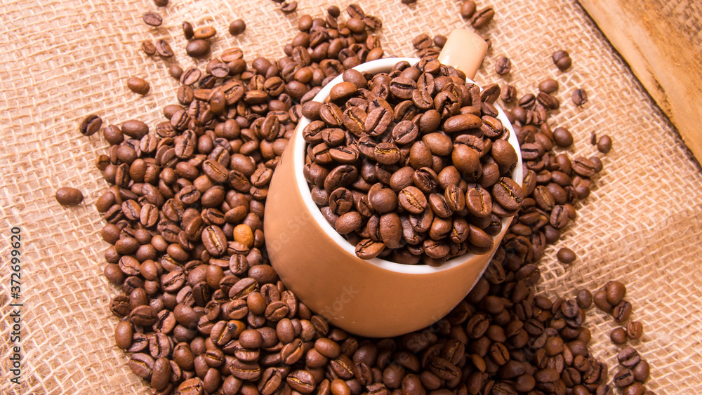 Mug full of coffee beans on the background of the bag,large Plenum Mug full of coffee beans on the background of the bag,large Plenum
