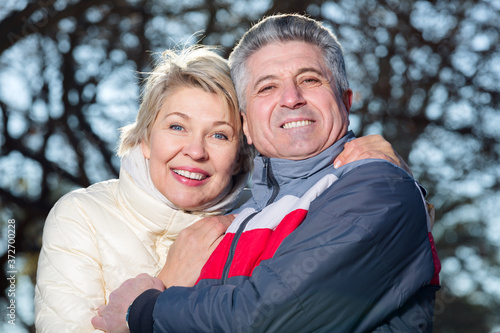 Smiling mature married couple embracing on sunny day in park