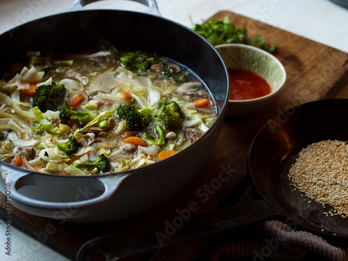 Asian vegetable soup with roasted sesame and hot sauce in natural light.