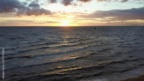 Dron Flying Over Sea in a Beautiful Sunset Kiteboarders Kiteserfing in the Backgroiund. Aerial Drone Shot. Sunrise Over the Sea. Colorful Sunset on the Baltic Sea, Latvia.