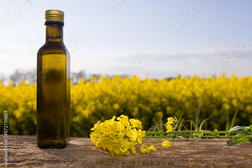 Rape oil and flower on wooden table with nature rape field background.