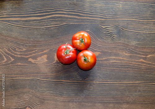 Three ripe tomatoes. View from above. Composition of vegetables on a wooden surface. Harvest concept of natural products. Horizontal orientation.