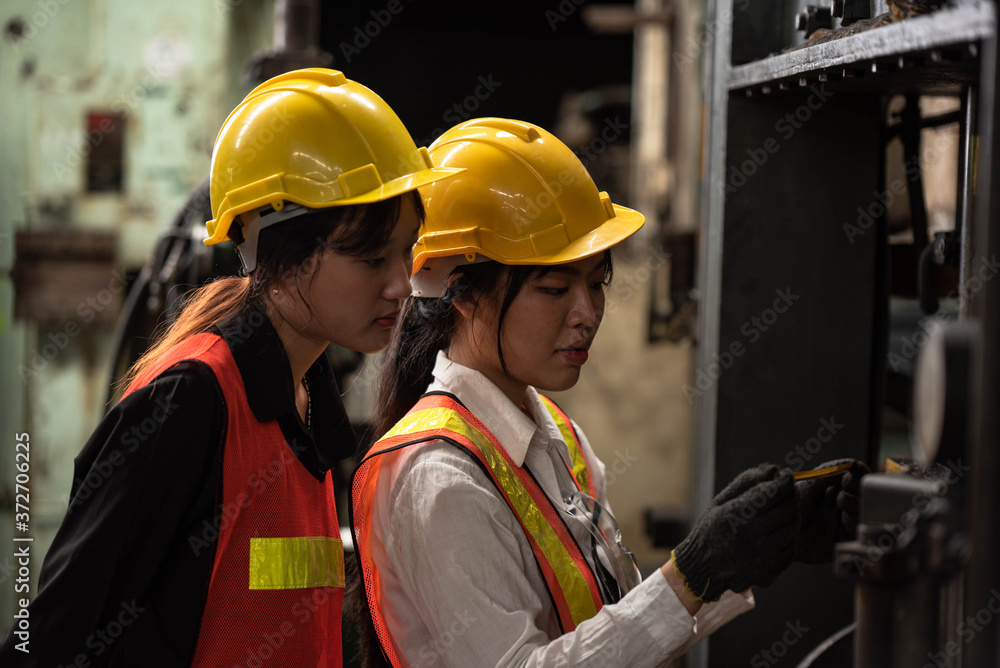 Obraz premium Portrait of young Asian technician women or industrial worker with hardhat and vest working machine in Factory of manufacturing place on Background