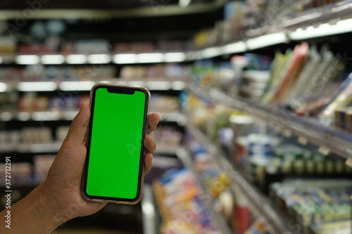 close up hand showing green screen smart phone at grocery store