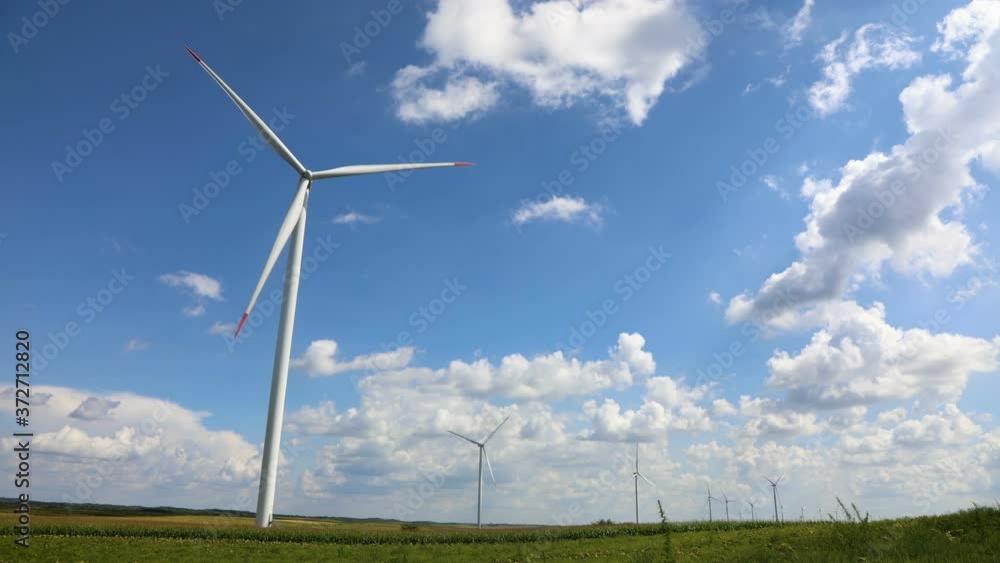 Wind generator farm time lapse with moving white fluffy clouds and blue sky Wind generator farm time lapse with moving white fluffy clouds and blue sky