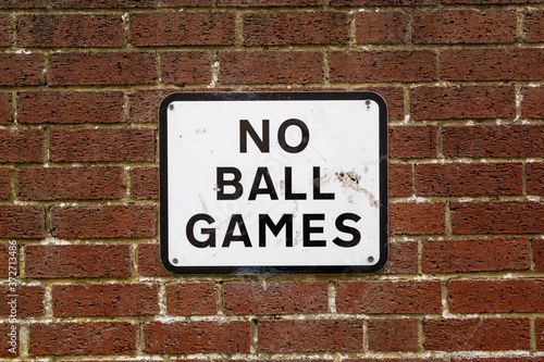 A No ball games sign on a brick wall on the side of a property