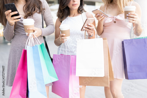 Friends With Shopping Bags Using Mobile Phones