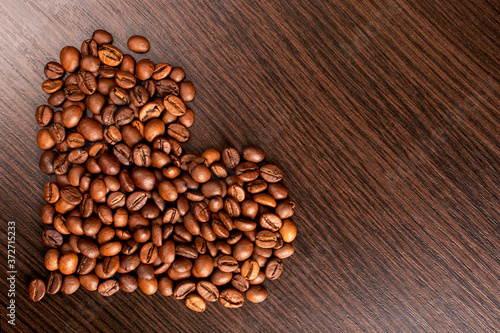 Heart shape made from coffee beans. Roasted Coffee beans background close up. International coffee day concept.