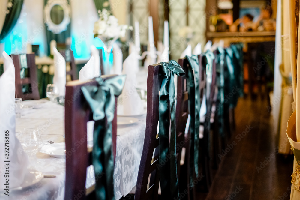 A row of chairs decorated with green ribbon. Banquet hall of the restaurant for special events. A row of chairs decorated with green ribbon. Banquet hall of the restaurant for special events.