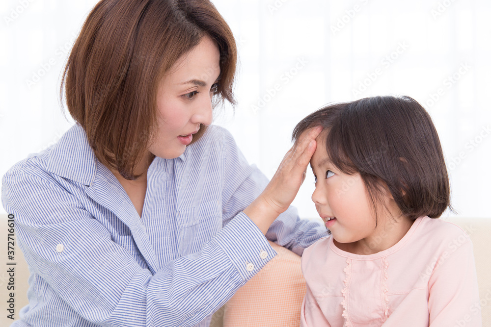 娘の熱を測る母 娘の熱を測る母