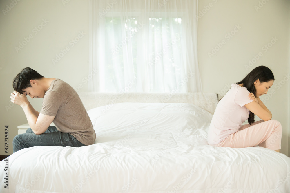 couple sitting on different sides of bed not talking after quarrel In bedroom couple sitting on different sides of bed not talking after quarrel In bedroom