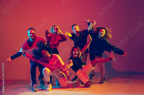 Fototapeta Naklejka Na Ścianę i Meble -  Young and crazy. Stylish men and woman dancing hip-hop in bright clothes on green background at dance hall in neon light. Youth culture, movement, style and fashion, action. Fashionable portrait.