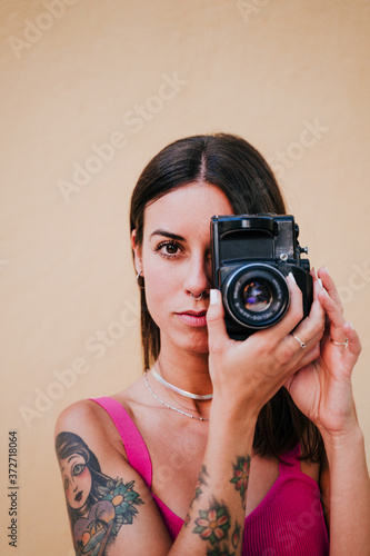 beautiful young woman outdoors taking a picture with old vintage camera. Technology and lifestyle