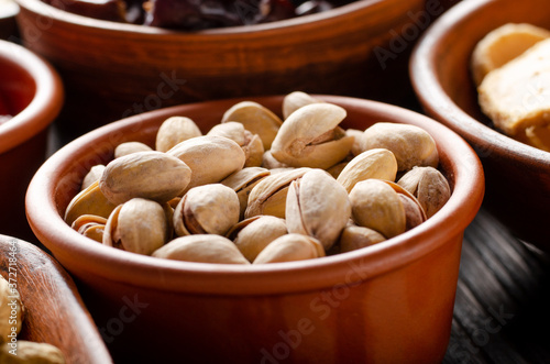 Pistachio nuts in clay bowl on kitchen wooden table food background
