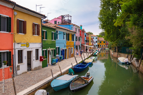 Burano, Italy - 09-18-2019 Colorful houses by canal in Burano, Italy. Burano is an island in the Venetian Lagoon and is known for its lace work and brightly colored homes.