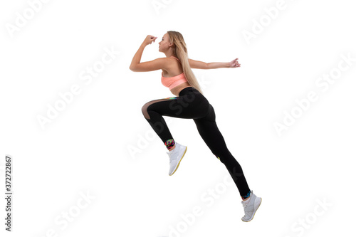 Sporty beautiful blonde in a pink top, leggings and sneakers runs forward on a white background