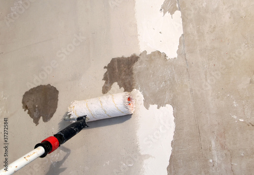 Paint roller on a concrete wall-primer,adhesive. photo