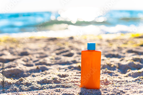 Protective sunscreen or sunblock and sunbathe lotion in orange plastic bottles on tropical beach, summer accessories in holiday