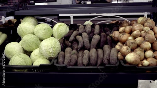 Various vegetables are on the counter in the store. Slow motion goes from onion to beetroot, cabbage then squash. A selection of vegetables, healthy food