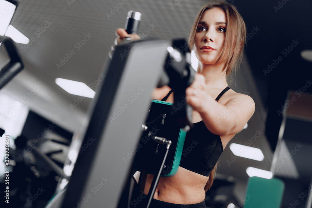 Young beautiful woman training her arms in a gym apparatus Young beautiful woman training her arms in a gym apparatus
