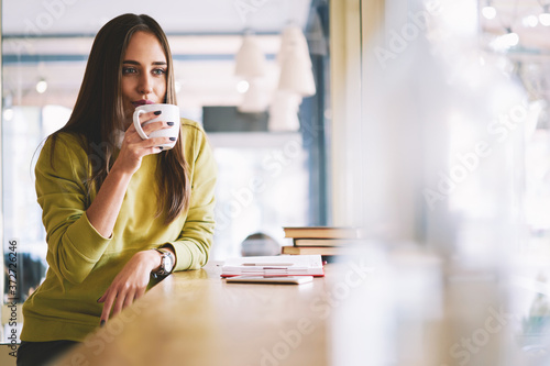 Portrait of successful owner of model agency resting during work break drinking coffee thinking about plans for day waiting for administrative assistant to discuss creative solution for new project