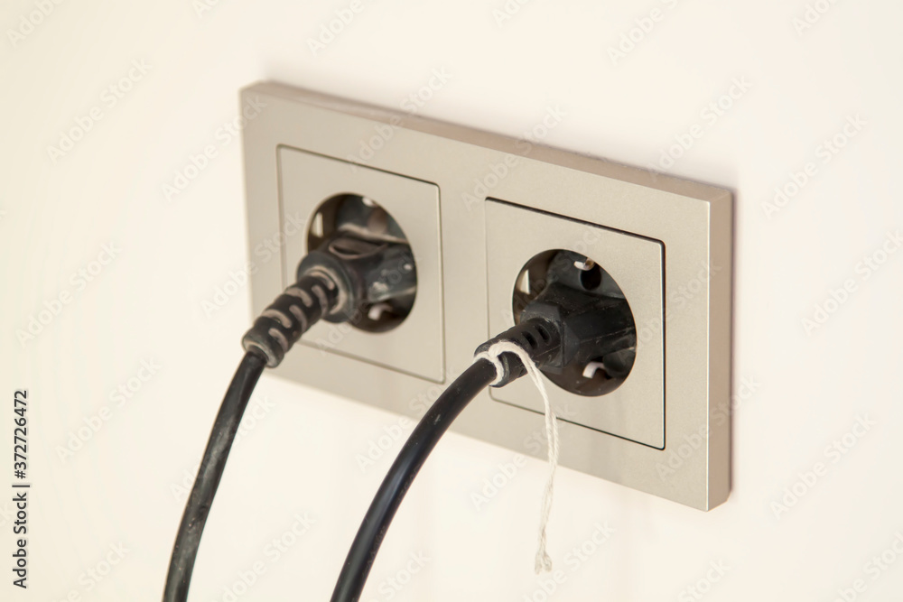 selective focus of two black plugs are plugged into a double electrical outlet with a frame selective focus of two black plugs are plugged into a double electrical outlet with a frame