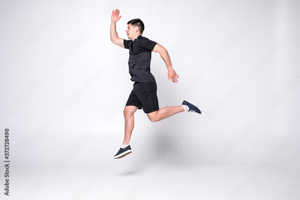 Fototapeta premium Happy young fitness man jumping isolated on a white background