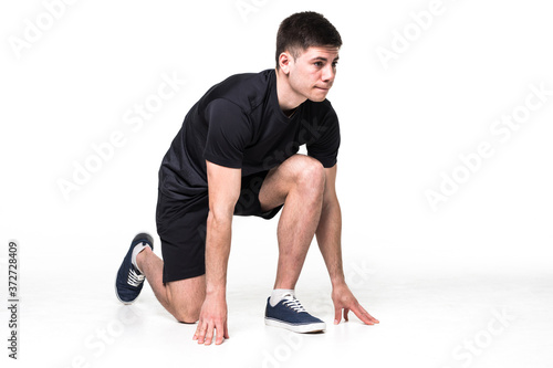 Full length portrait of a male athlete ready to run on white background