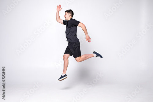 Happy young fitness man jumping isolated on a white background