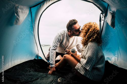 Travel couple people with camping activity kissing and having relax together - two adult with tent camp enjoy holiday vacation in total freedom