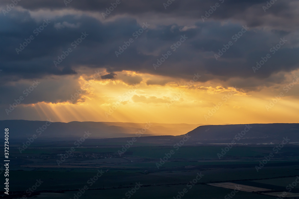 Amazing long shot of sunlight and sun beams in sky at sunset over green field