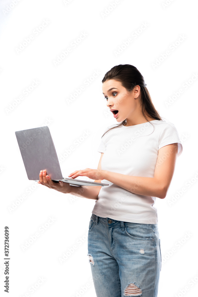 shocked brunette woman in white t-shirt using laptop isolated on white shocked brunette woman in white t-shirt using laptop isolated on white