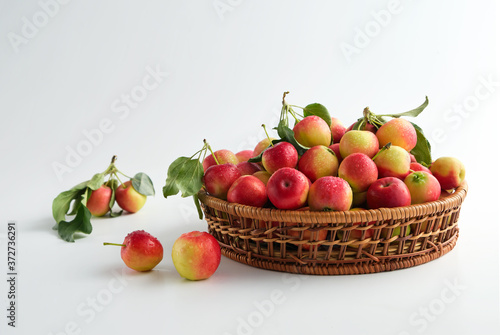 Red and yellow ripe apples with leaves close-up in a wicker basket on a light top view. No people