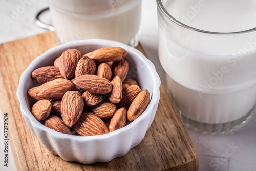 Close up. Almonds in a white ceramic cup and a milk glass.
