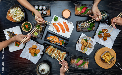 Top view of people eating Japan food on wood table together.