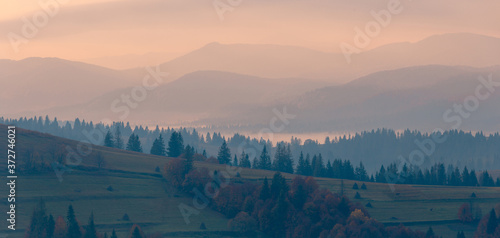 Mountain hills and morning fog at beautiful autumn foggy scenery. Wide panorama mountain range. Colorful Carpathian mountain range with tonal perspective.