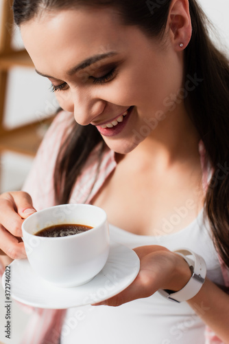brunette young woman holding cup of coffee with saucer